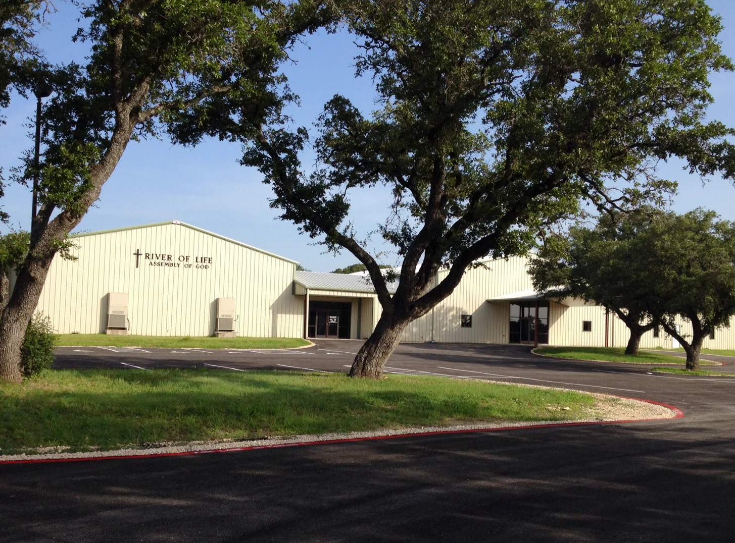 River of Life’s church building shaded by oak trees on Airport Road
